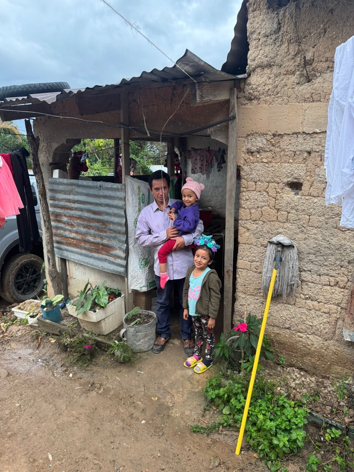 Man with two children outside a modest home