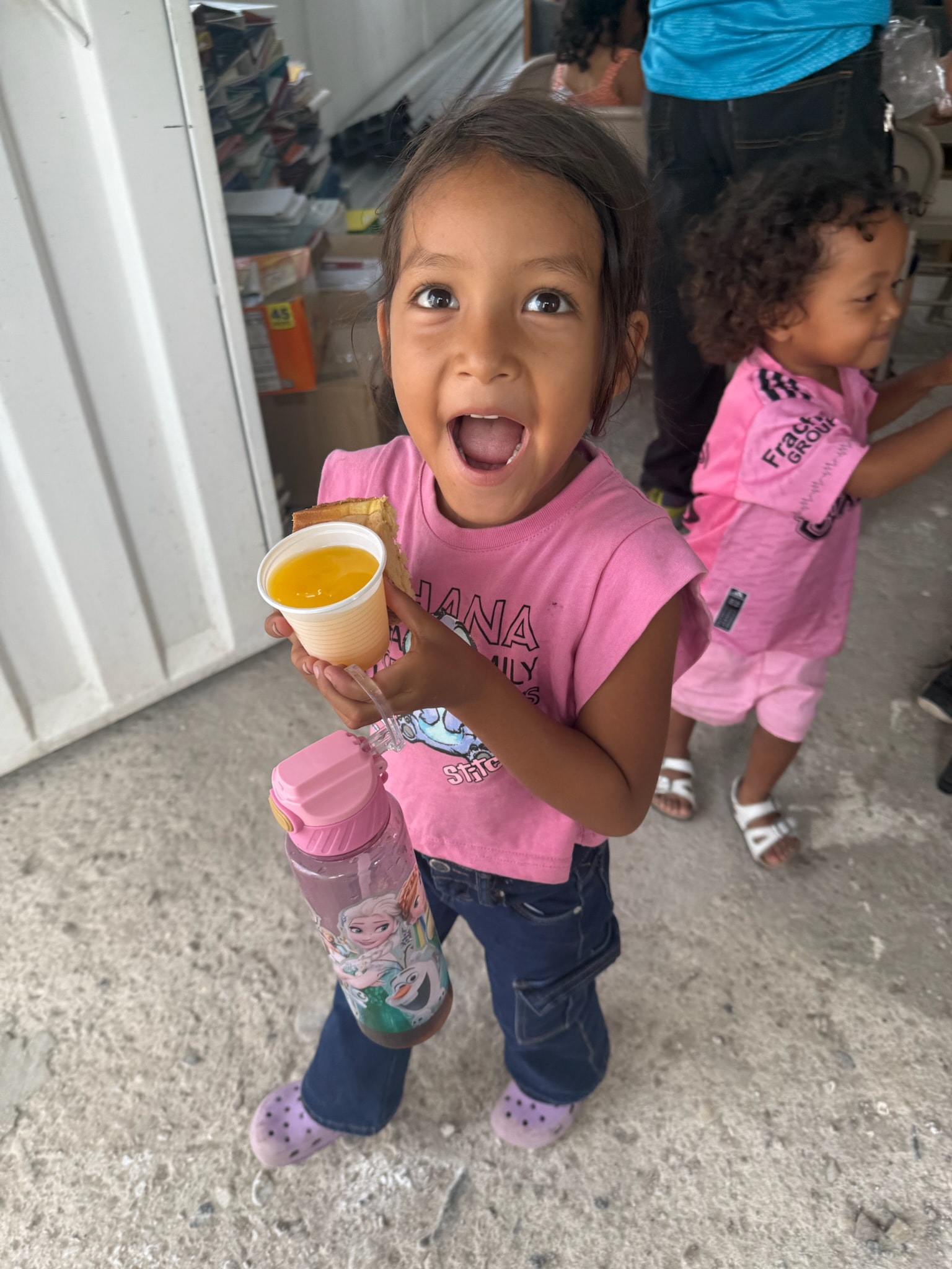 Child excited holding a juice cup indoors