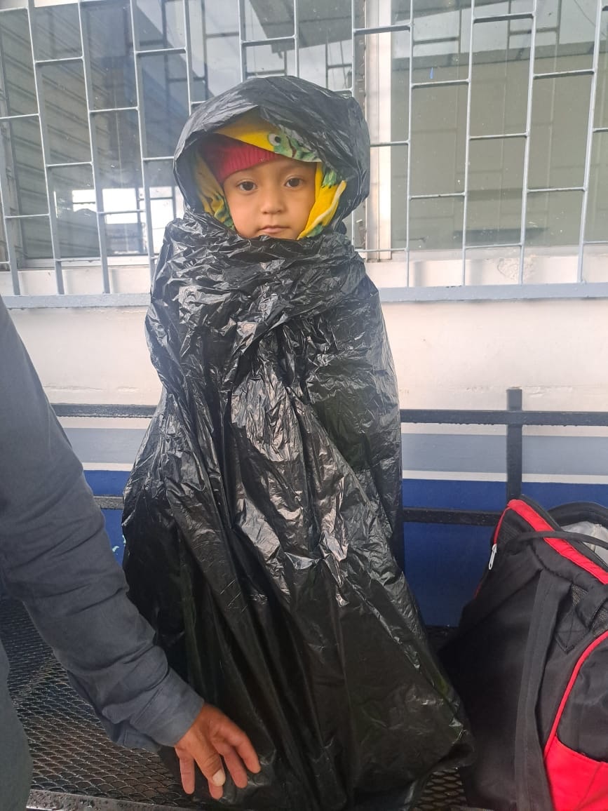 Child wrapped in a black plastic bag indoors