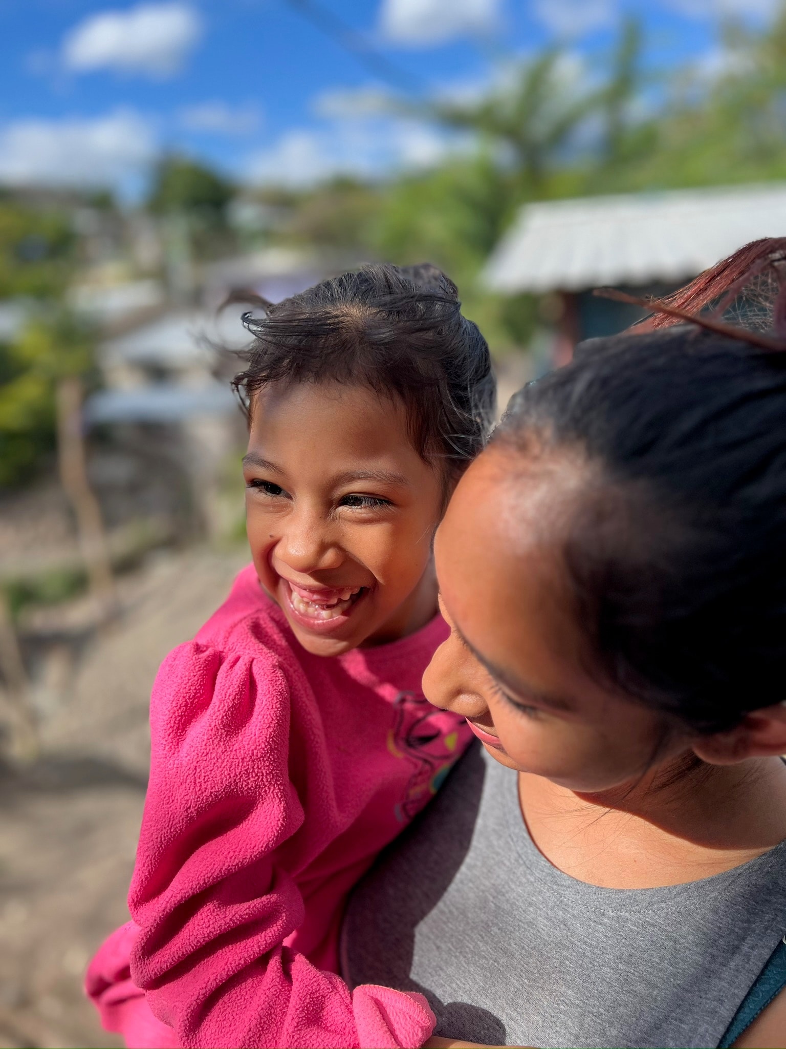 Child laughing with a parent in a rural village