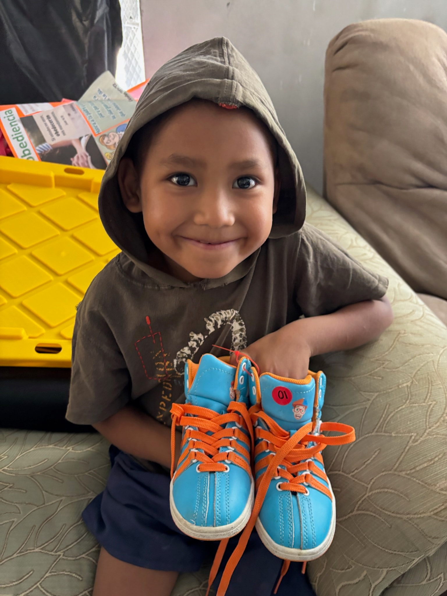 Child holding oversized sneakers — a gift from the mission team